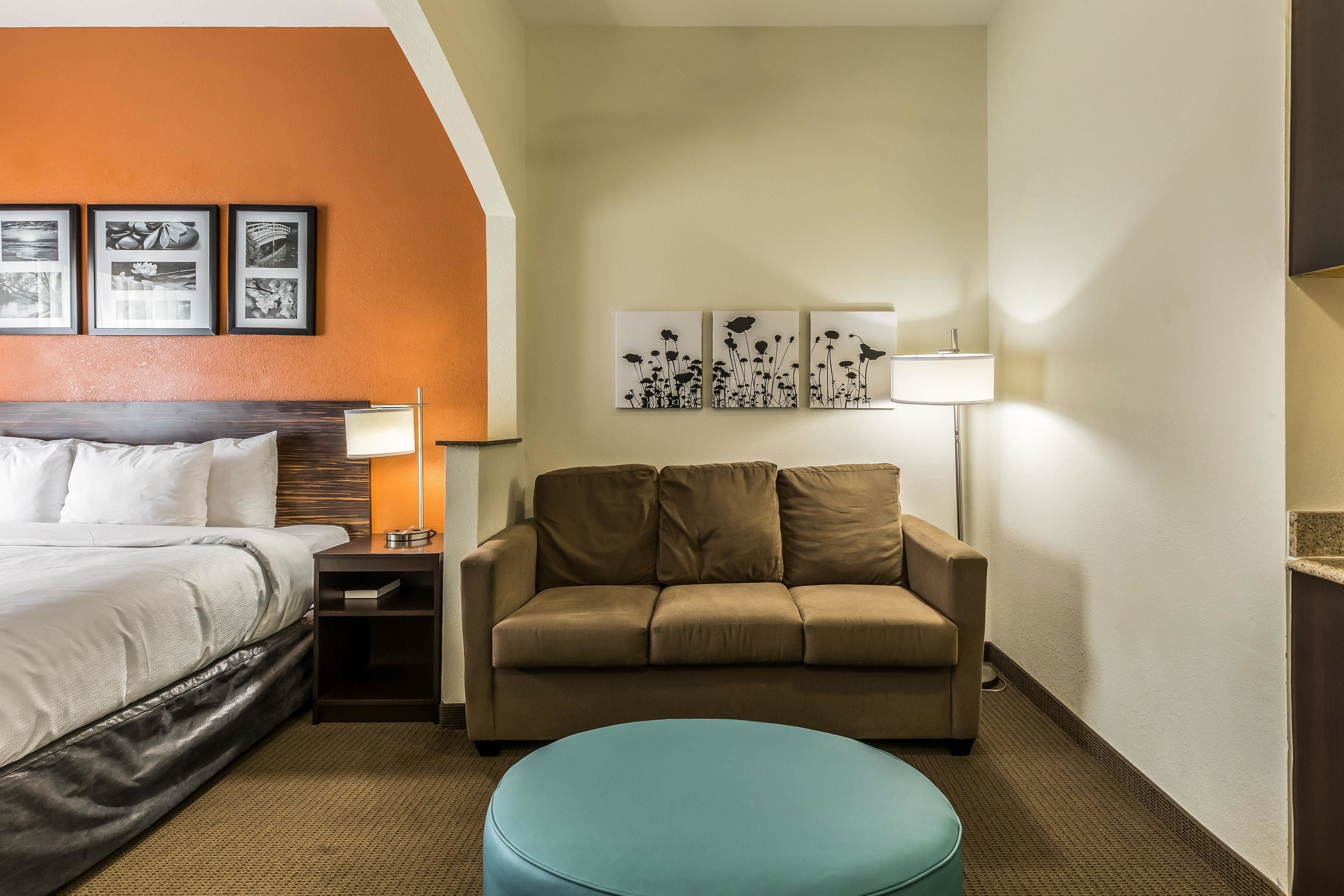 Een hotelkamer met een bed, een bank, een kleine tafel en wanddecoratie.