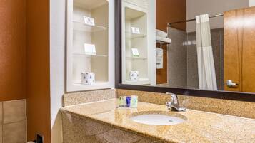 Un baño con lavamanos de encimera de granito, un espejo y un perchero para toallas.
