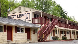 Ein Motel mit einem 'Nächste Abzweigung' Schild, einer Treppe und einem Parkplatz.