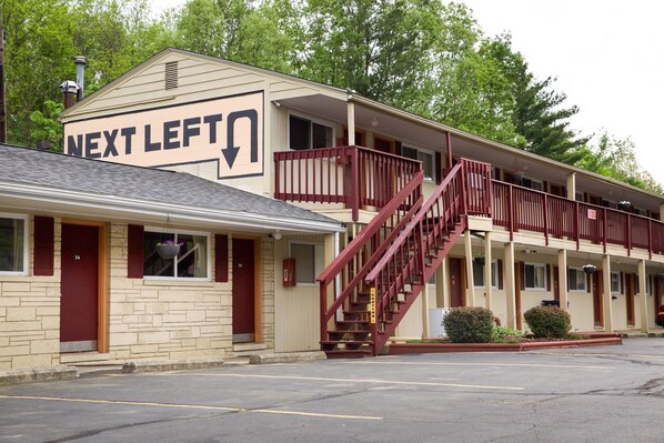 A motel with a 'Next Left' sign, a staircase, and a parking lot.