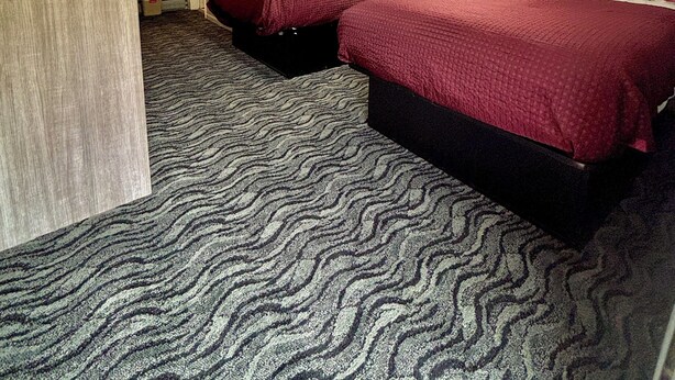 Ein Hotelzimmer mit zwei Betten, einem Schreibtisch und einem Spiegel.
