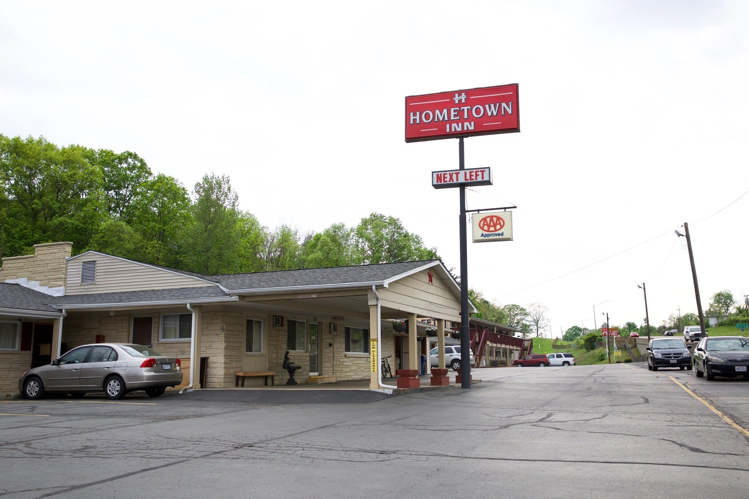 A motel with a covered parking area, a sign for AAA approval, and a bench outside.