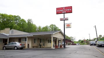 A motel with a covered parking area, a sign for AAA approval, and a bench outside.