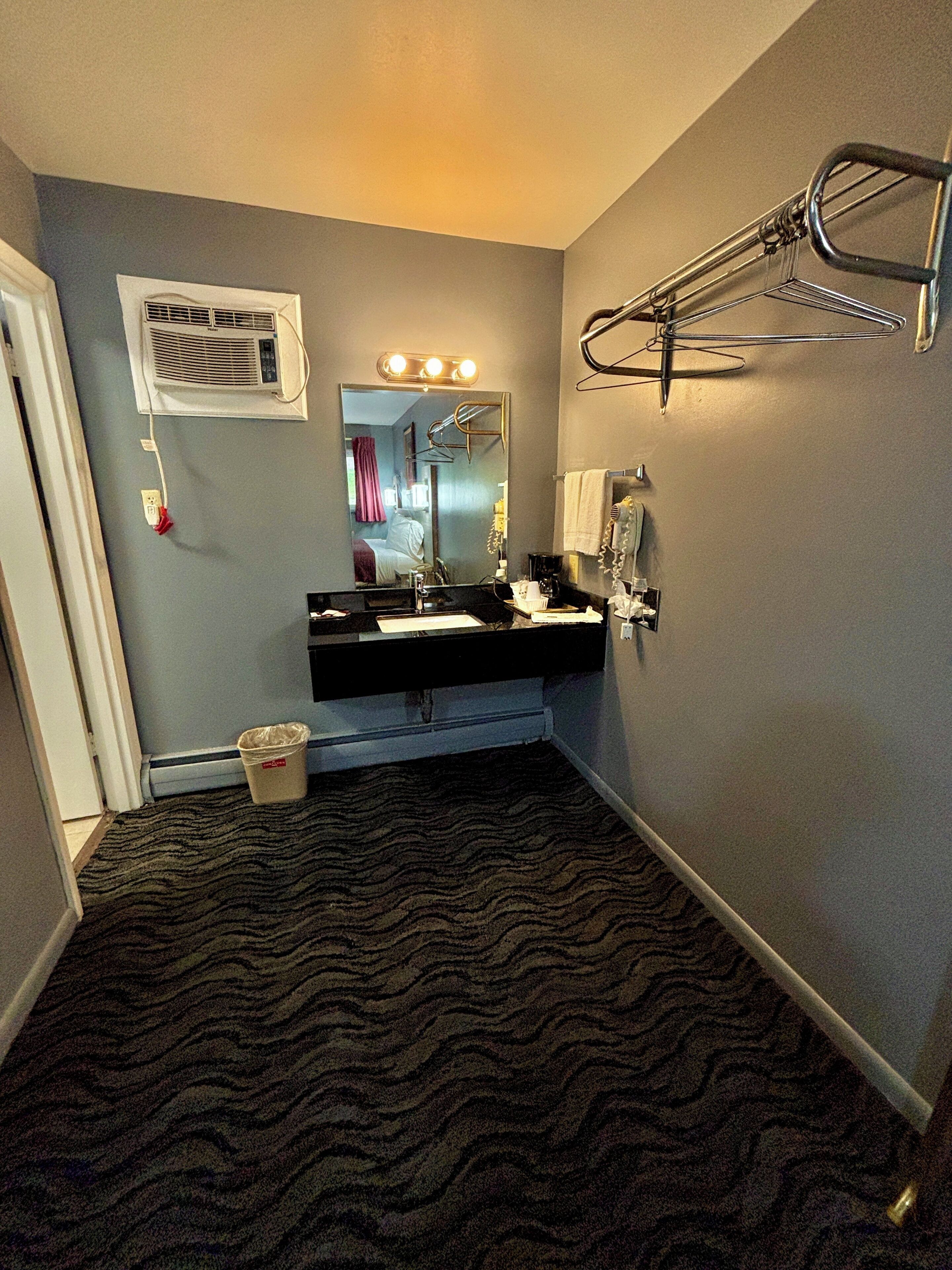 Un bagno d'hotel con un mobile lavabo nero, uno specchio, un porta asciugamani e un asciugacapelli.
