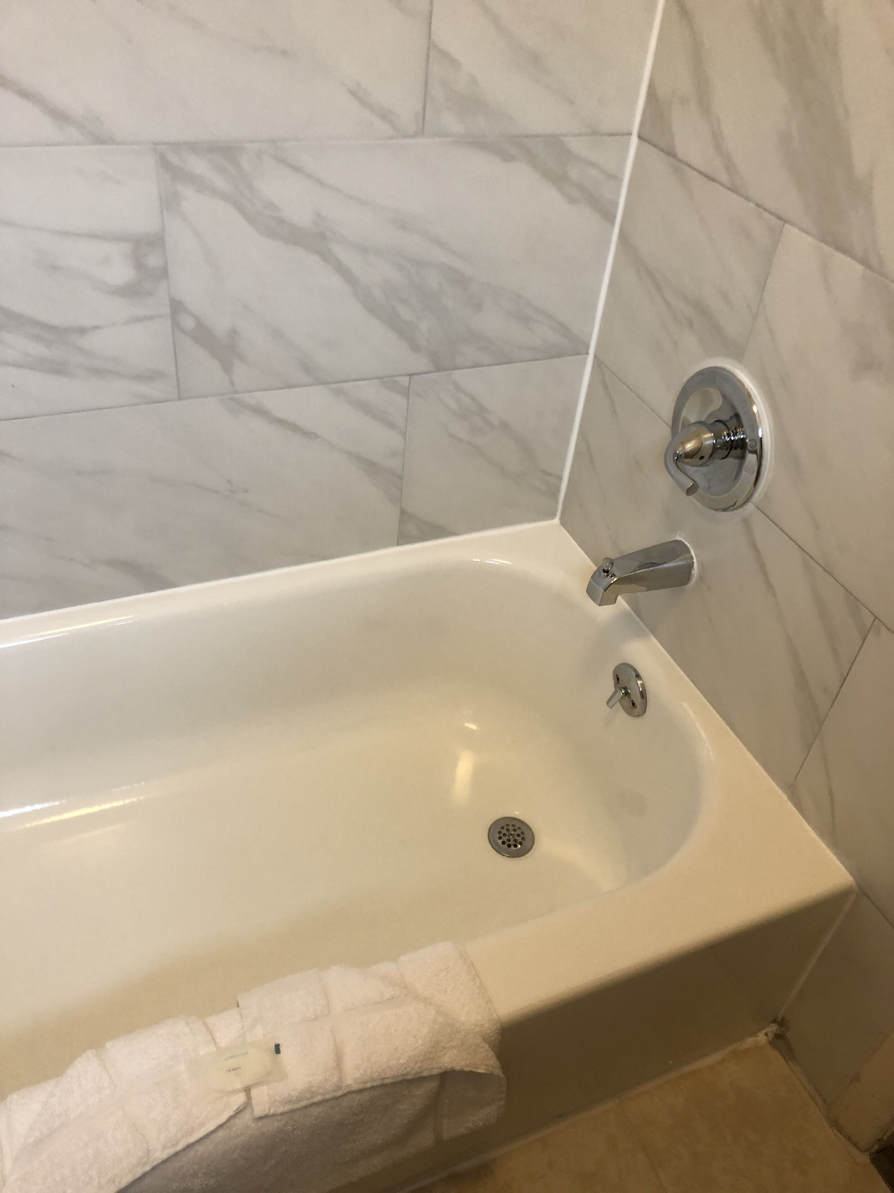 Een aparte badkuip en douche, een haardroger, handdoeken