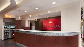 Ein Empfangsbereich mit einer Marmor-Theke, einem mit Getränken gefüllten Kühlschrank und einem Schild mit der Aufschrift "RAMADA".