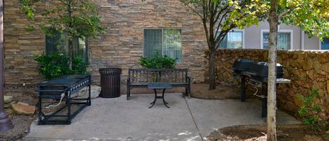 A patio area with a stone wall, a bench, a grill, and a lamp post.