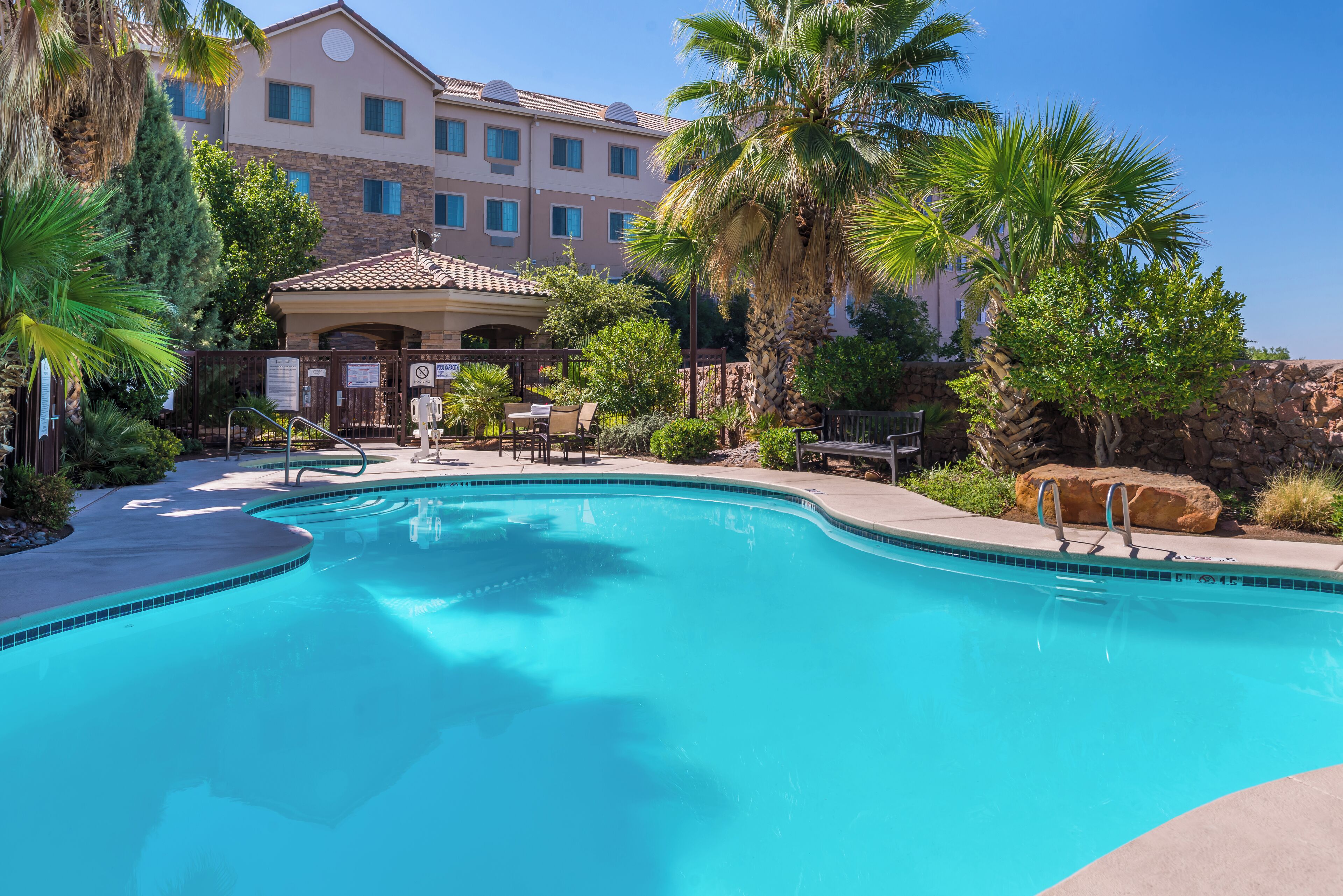 Una piscina al aire libre, sombrillas, sillones reclinables de piscina