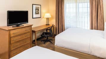 A hotel room with a bed, a desk with a chair, a television, and a lamp.