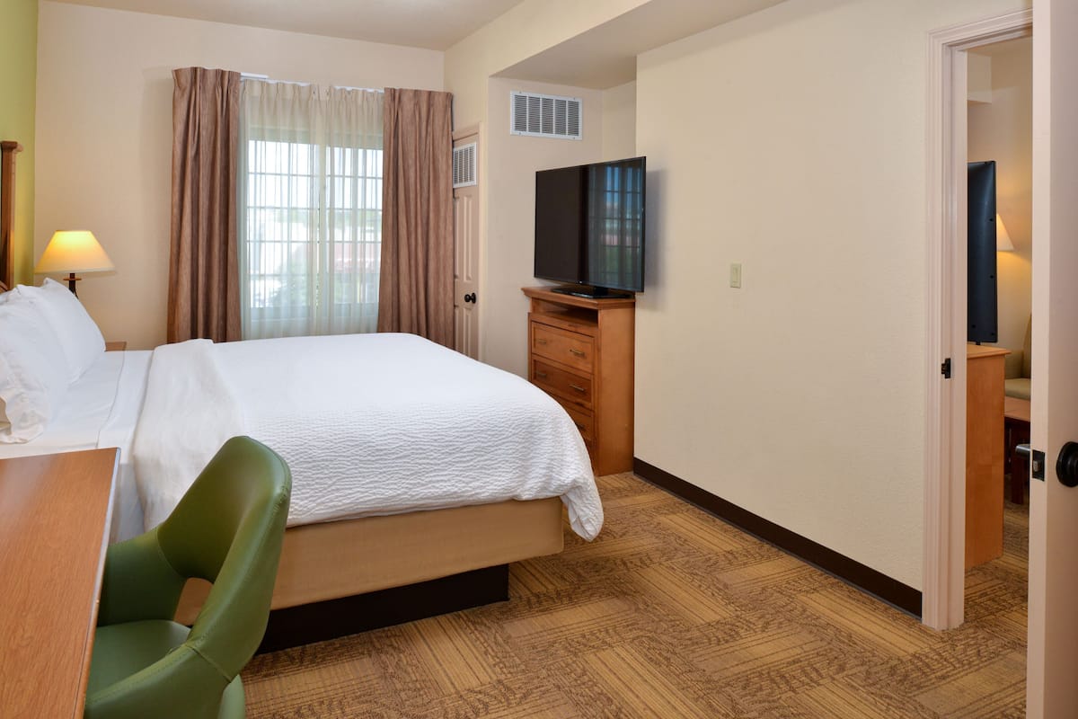 A hotel room with a bed, a television, a desk, and a chair.