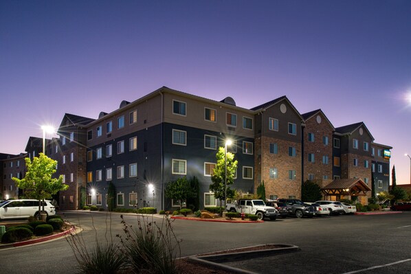 A multi-story hotel with a parking lot, several vehicles, and well-maintained landscaping.