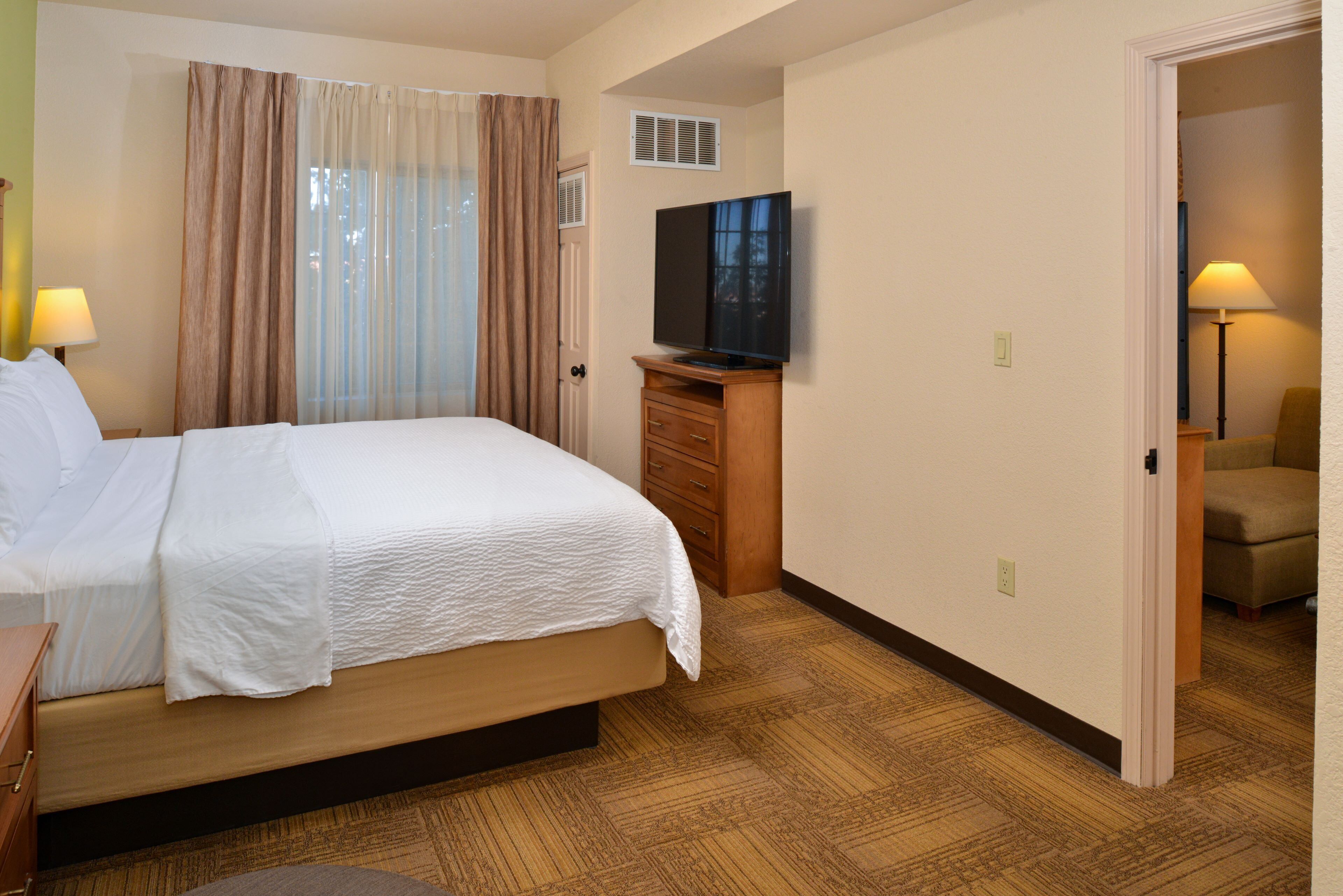 A hotel room with a bed, a television, a desk, and a chair.