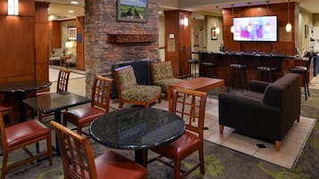 A lobby with a stone wall, a television, and a bar area with stools.