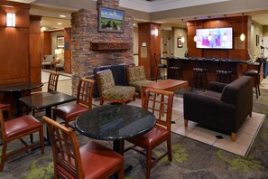 A lobby with a stone wall, a television, and a bar area with stools.