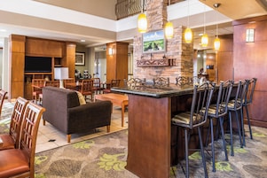Un vestíbulo de hotel con zona de bar, áreas de descanso y chimenea.