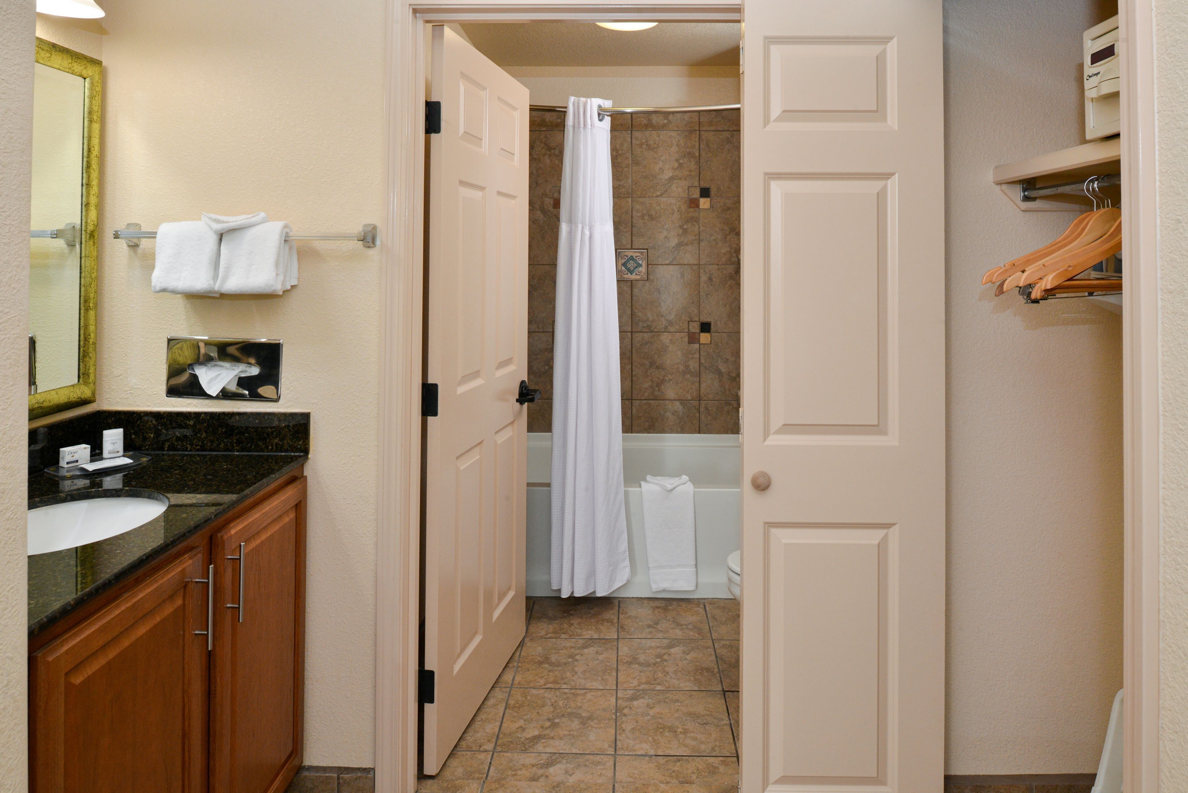 A bathroom with a sink, mirror, towel rack, shower curtain, and a toilet.