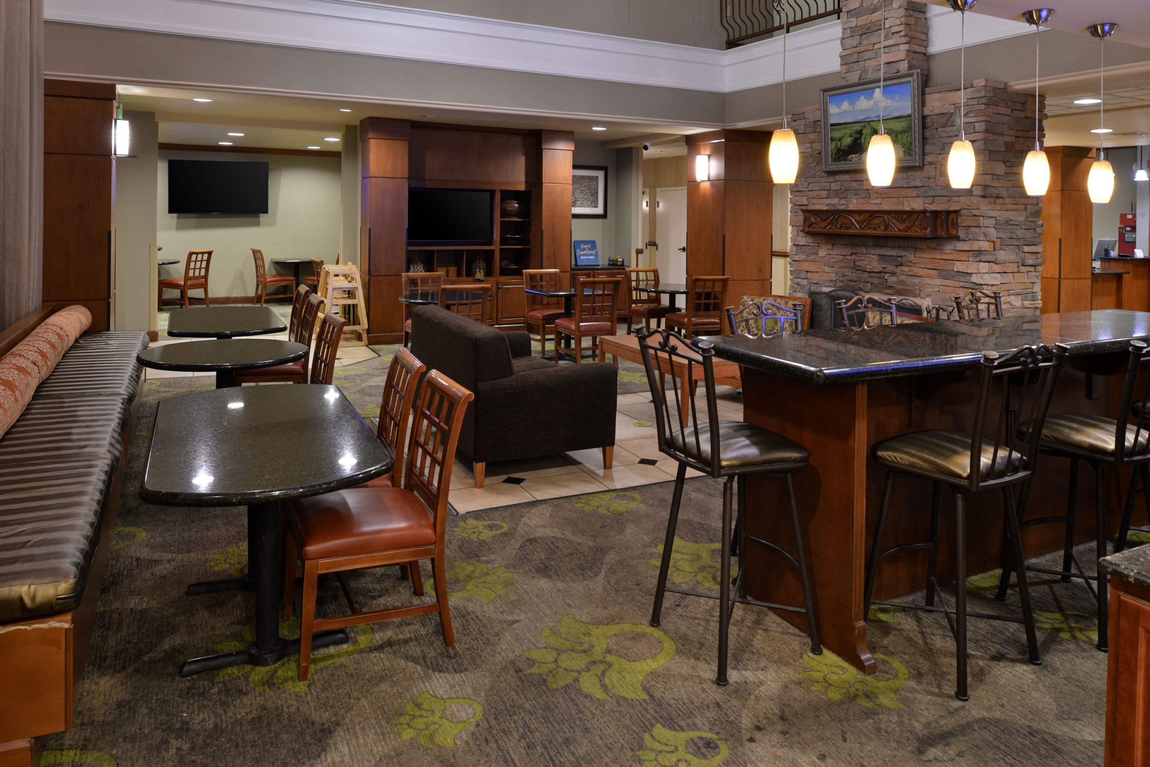 A hotel lobby with a bar area, seating arrangements, and a television mounted on the wall.