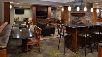 A hotel lobby with a bar area, seating arrangements, and a television mounted on the wall.