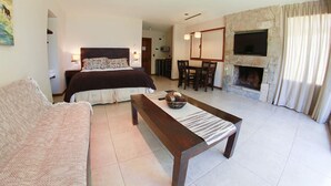 Een slaapkamer met een bed, een bank, een eettafel en een open haard.