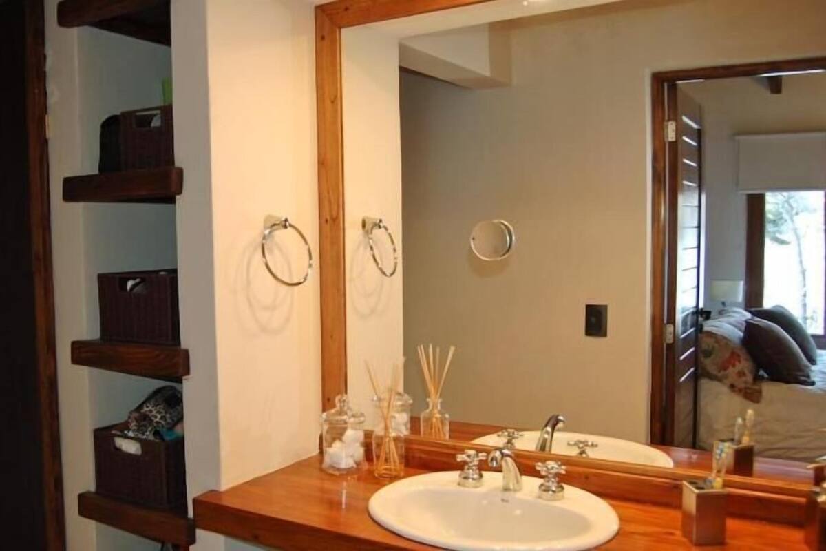 Une salle de bain avec un meuble-lavabo en bois, un grand miroir et un évier.