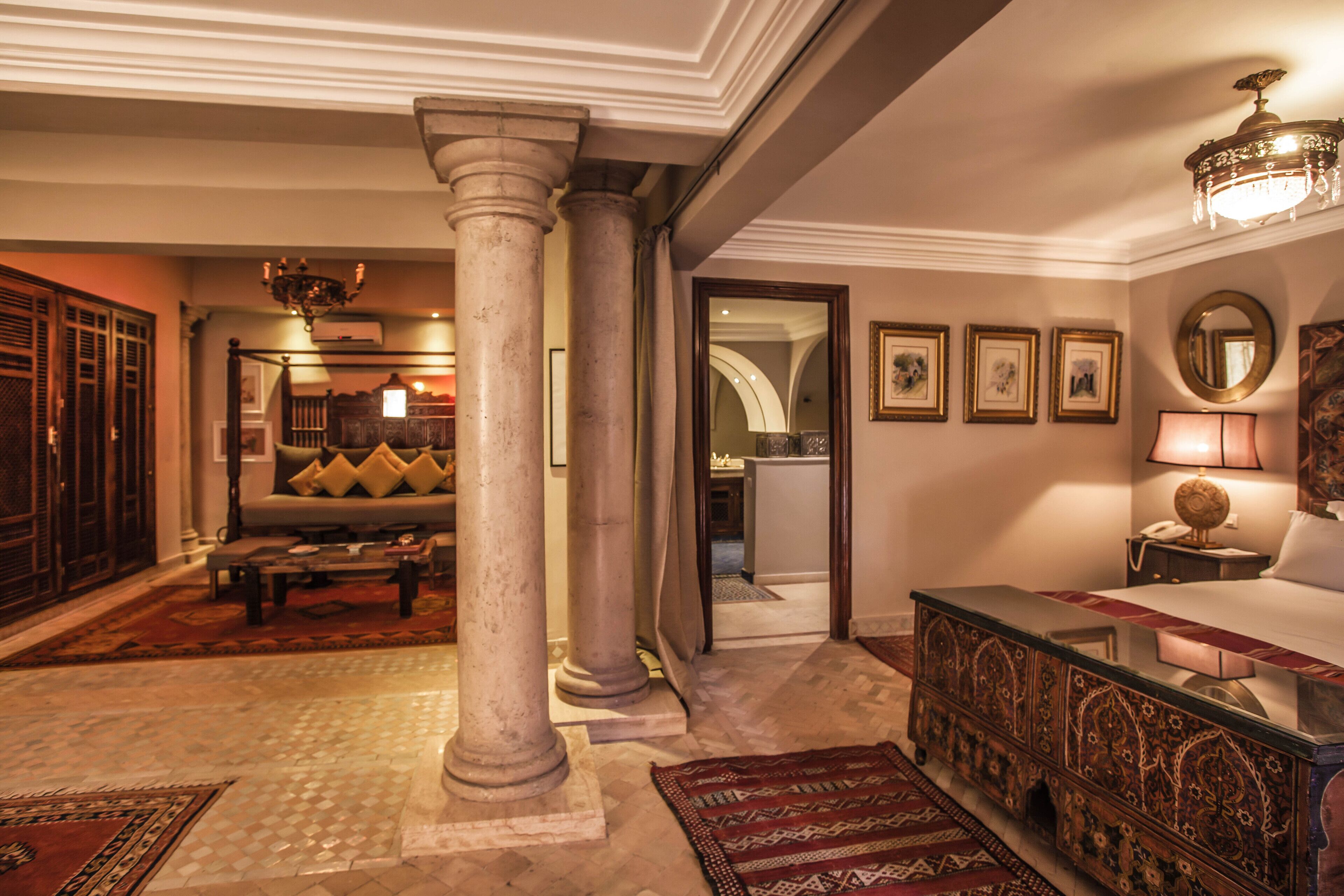 Un hall d’entrée spacieux, agrémenté d’une imposante colonne, d’un canapé aux coussins à motifs, d’un lustre et d’une console décorative.