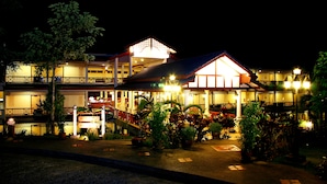 A multi-story hotel with a covered outdoor area, potted plants, and a well-lit entrance. - Khaolak Sunset Resort - Adults Only (SHA Extra Plus) (Takua Pa)