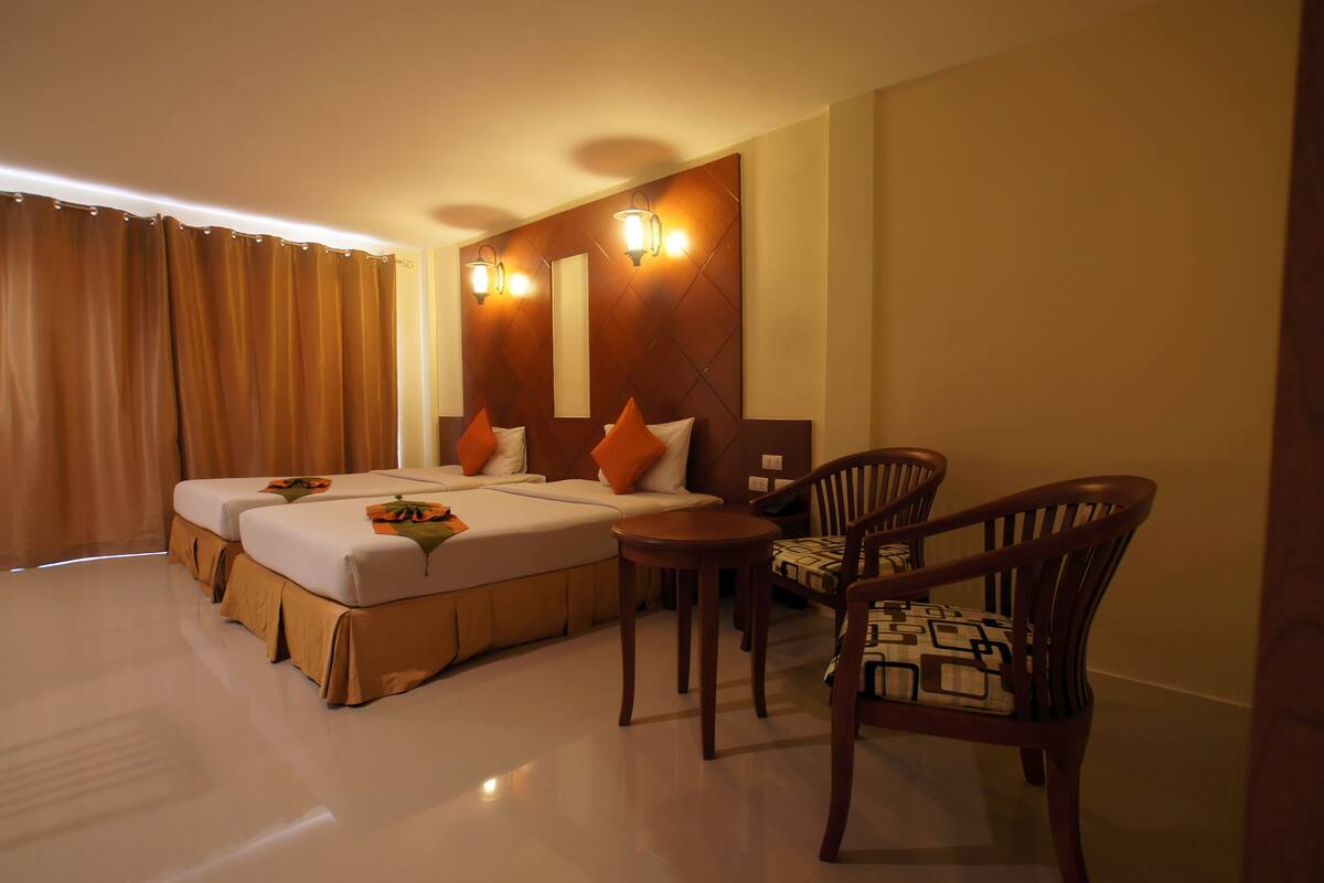 A hotel room with two beds, a small table, two chairs, and a mirror on the wall.