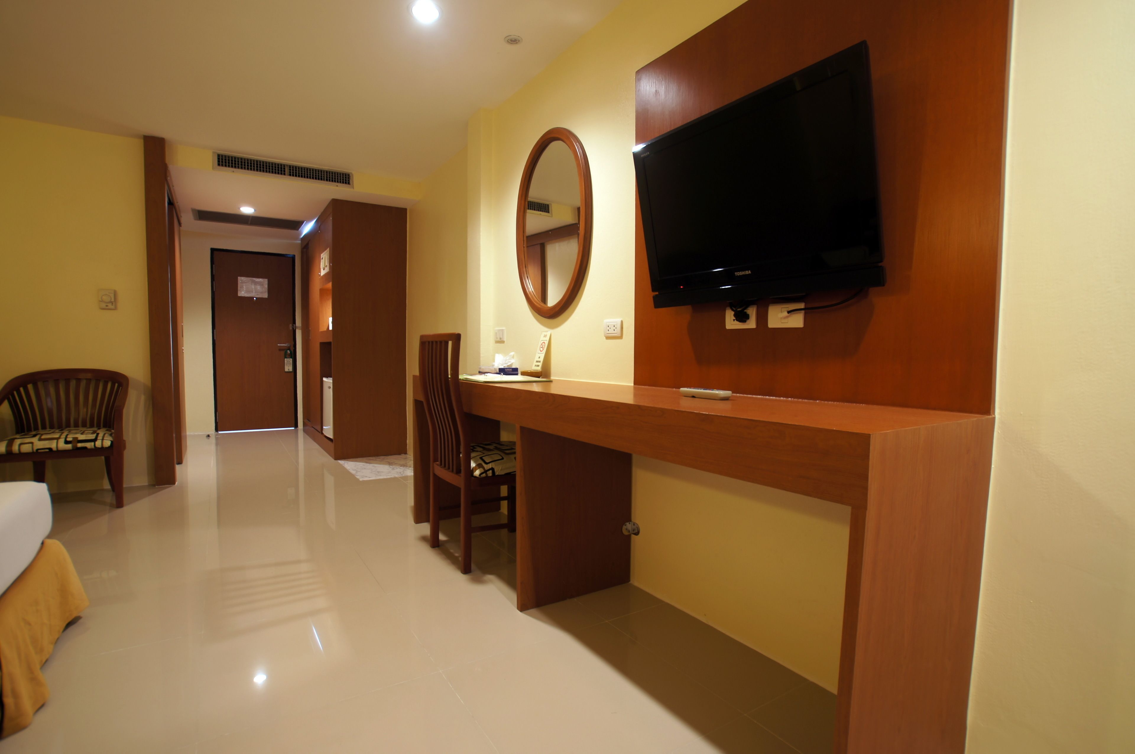 A hotel room with a bed, a desk, a chair, a television, and a mirror.