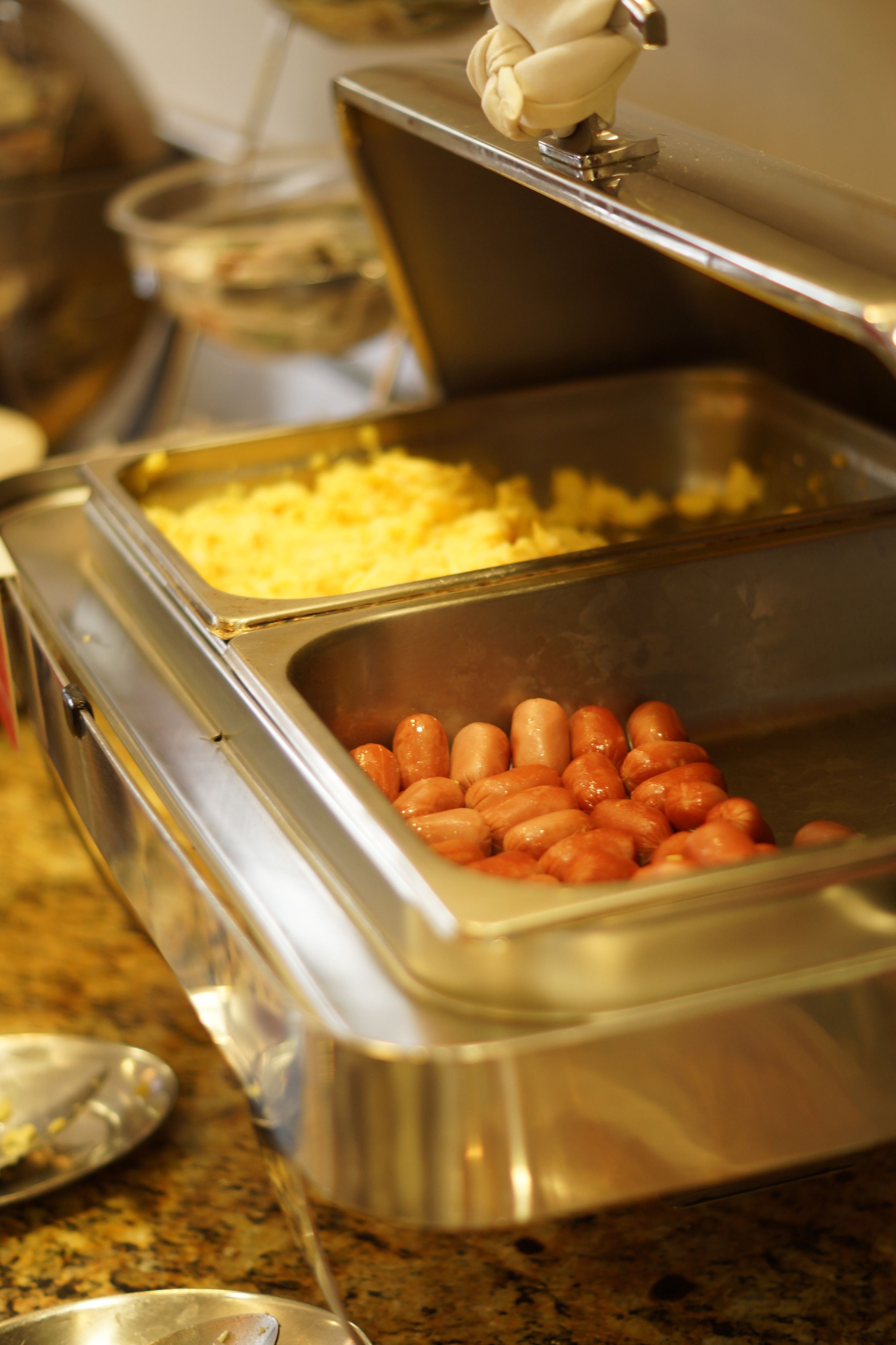 A buffet with various food items including hot dogs and macaroni.