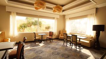 Habitació d'hotel amb una finestra gran, un sofà, una taula de menjador i cadires.
