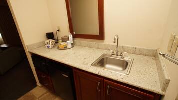 A kitchen with a granite countertop, stainless steel sink, and wooden cabinets.