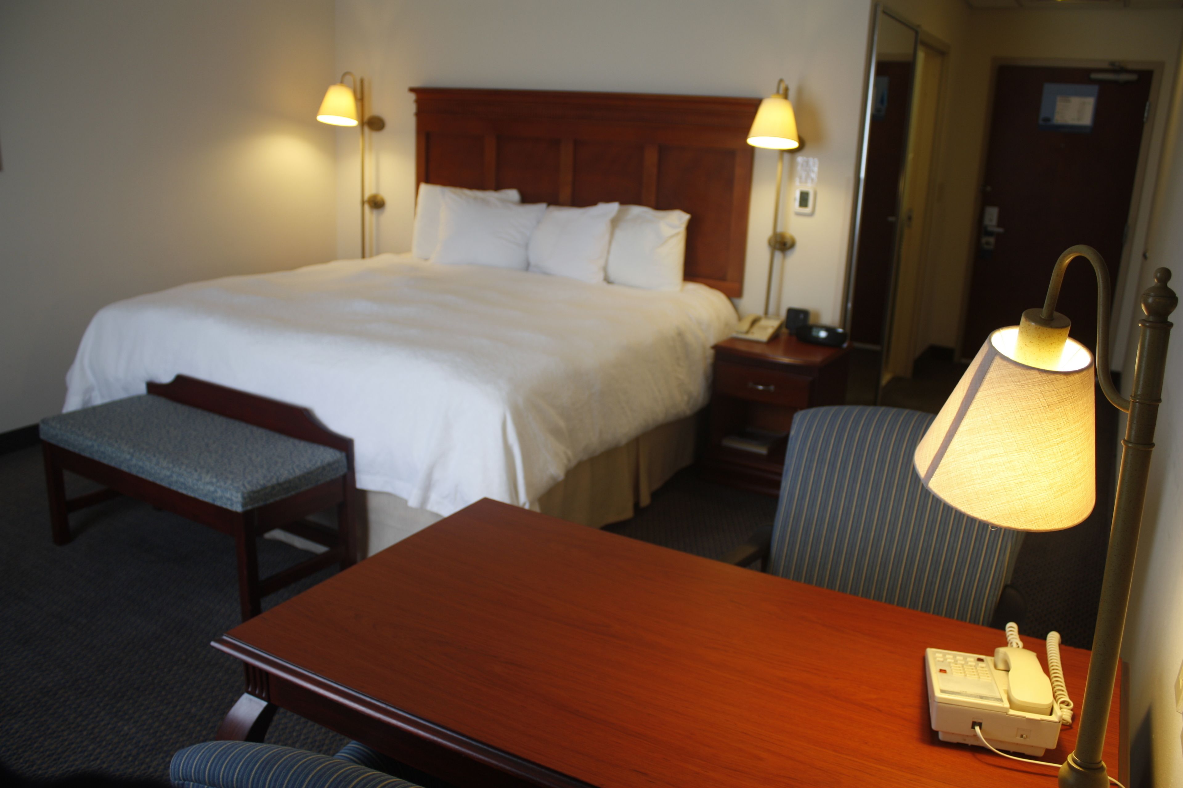 A hotel room with a large bed, bedside tables, a desk, and a chair.