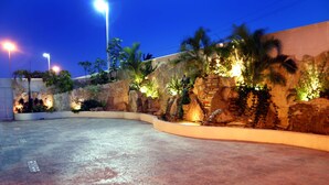 Un espacio al aire libre con muro de piedra, palmeras y suelo empedrado.