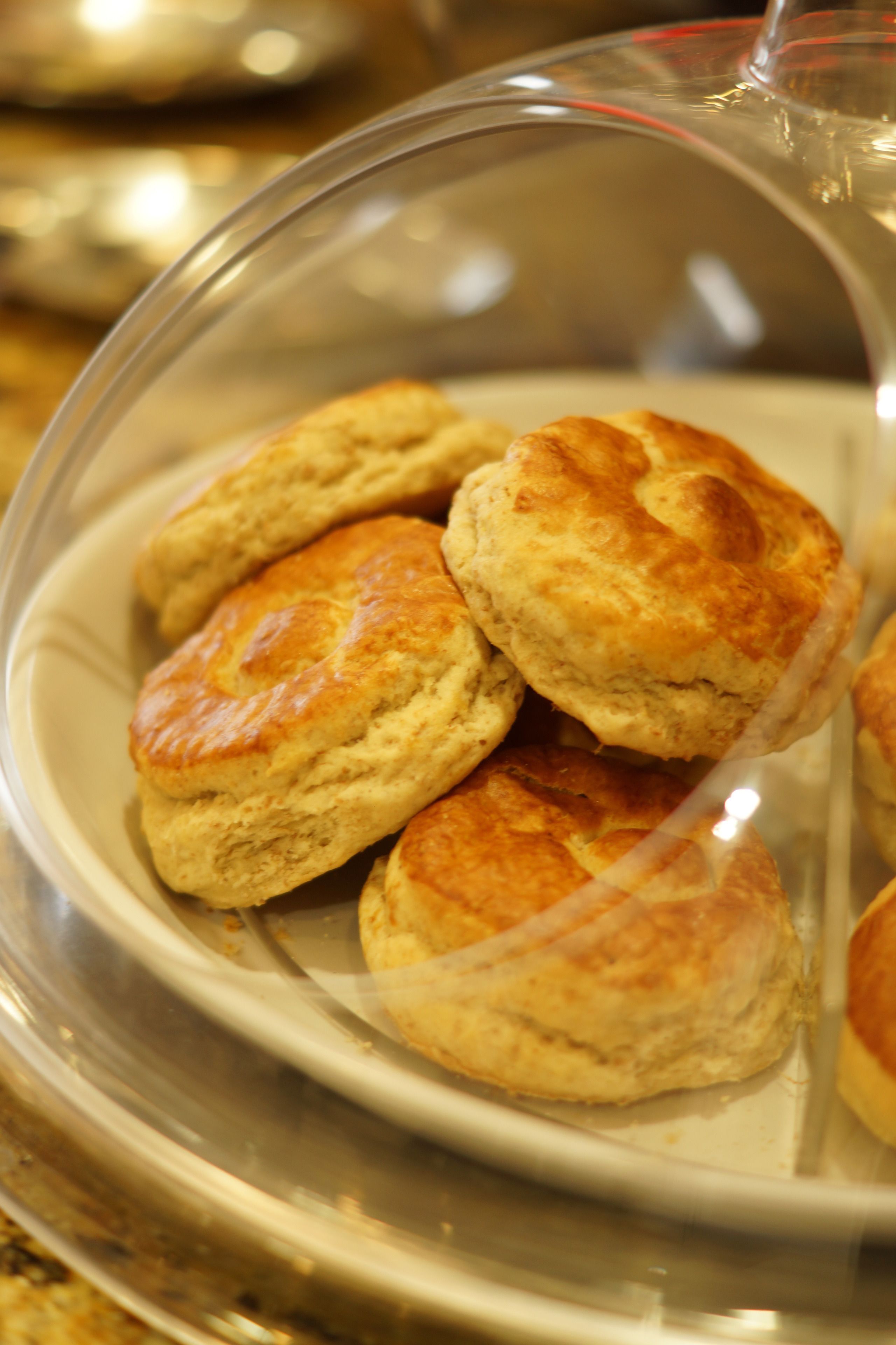 A clear glass dome covering a plate of freshly baked biscuits.