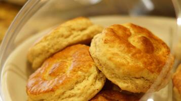 A clear glass dome covering a plate of freshly baked biscuits.
