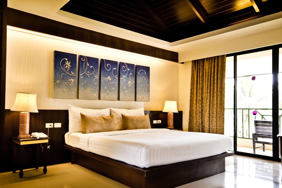 Un hotel moderno con una cama grande, dos mesitas de noche con lámparas, un adorno en la pared y vistas al exterior.
