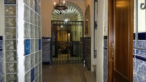 A hallway with a tiled wall, a wooden door, and a metal gate leading to a room. - Hotel Nova Centro (Jerez de la Frontera)