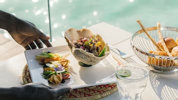 A table with food items, a glass of water, and a view of the water.