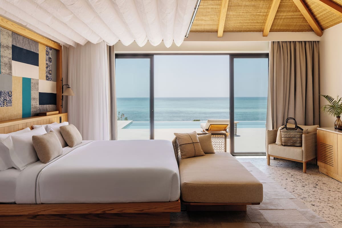 Ein Schlafzimmer mit einem großen Bett, einer Couch, Meerblick und einem Balkon mit einem Stuhl.