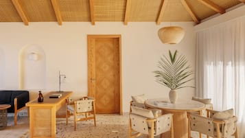 A room with a wooden ceiling, a round table with chairs, a door, and a potted plant.