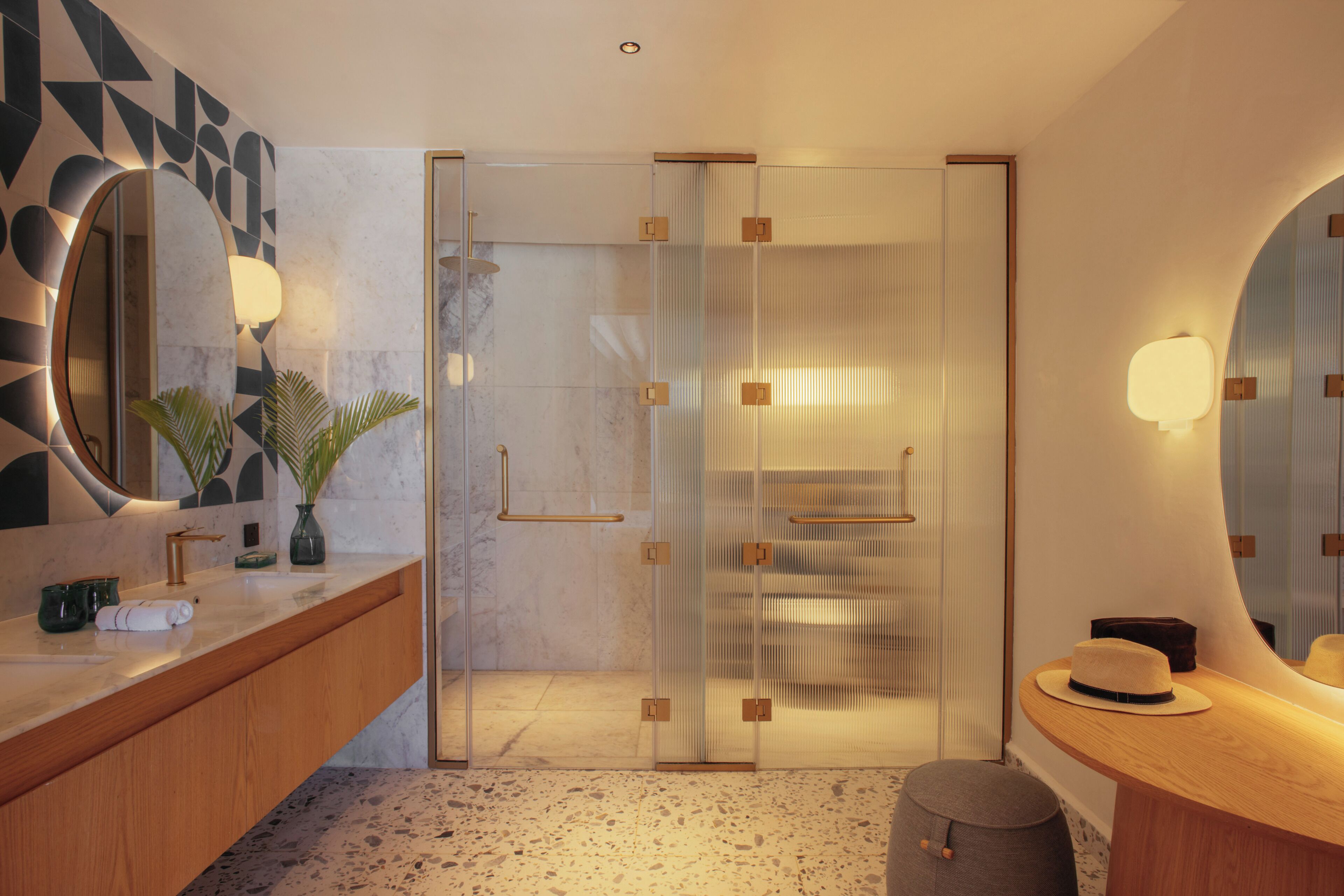 Une salle de bain moderne avec un comptoir en marbre, un grand miroir et une douche dotée de parois en verre.