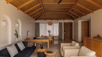 Un'ampia zona giorno con soffitto alto, un tavolo da pranzo, divani e angolo cottura.