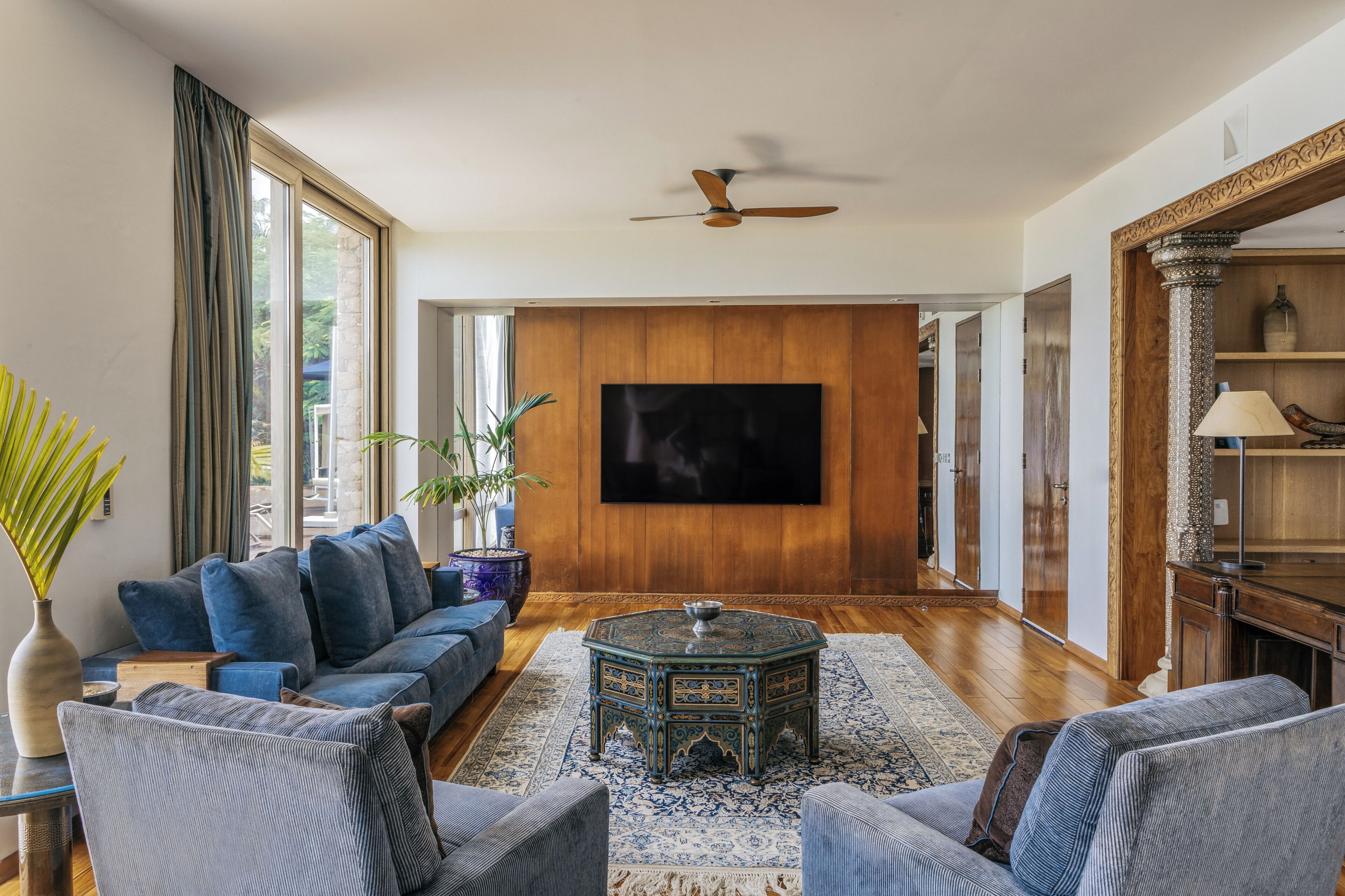 A spacious living room with a large TV, comfortable seating, and a decorative floor rug.