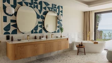 Un baño moderno con una bañera independiente, un espejo grande y un salpicadero de azulejos geométricos.