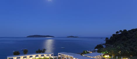 A resort with an infinity pool, outdoor seating, and a view of the sea.