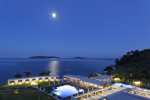 A resort with an infinity pool, outdoor seating, and a view of the sea.