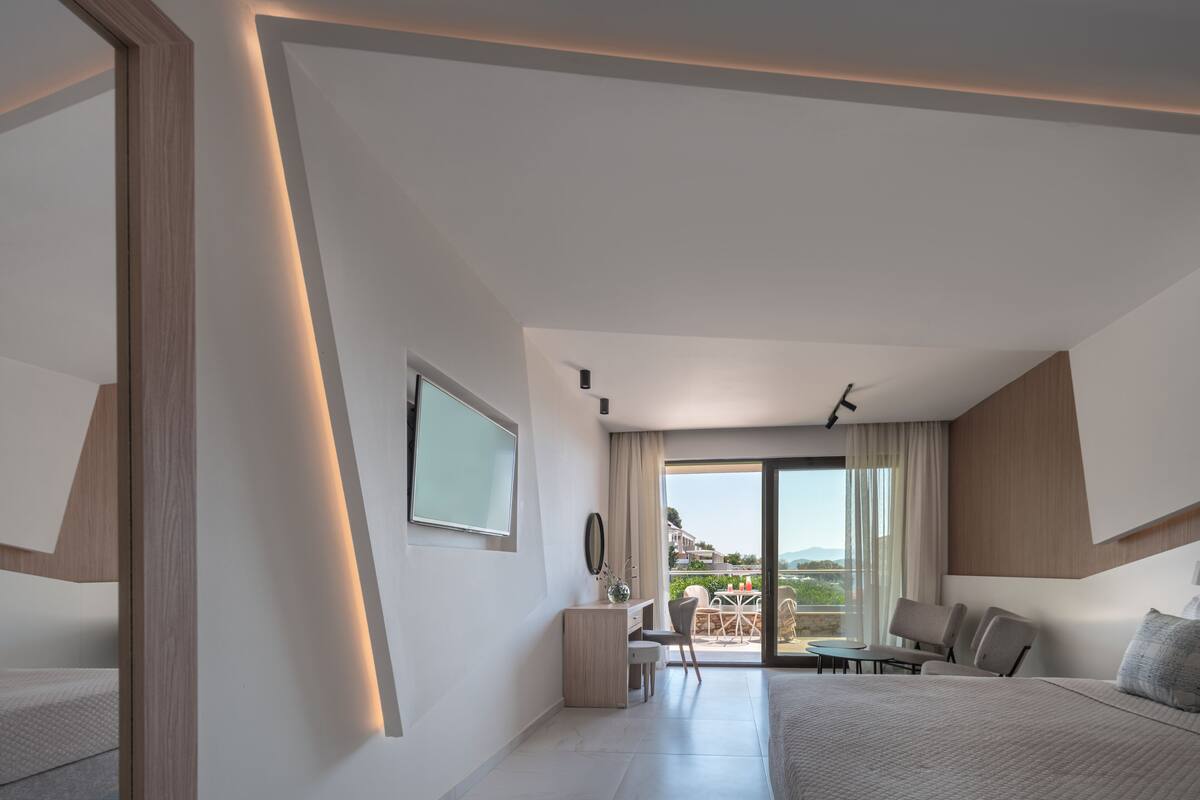 A modern hotel room with a bed, desk, and seating area.