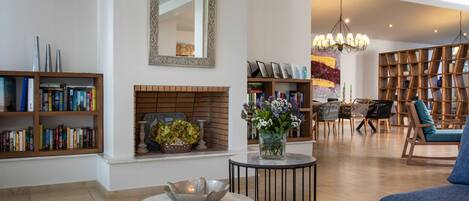 A spacious living area with a fireplace, bookshelves, a coffee table, and a seating area with a blue sofa.