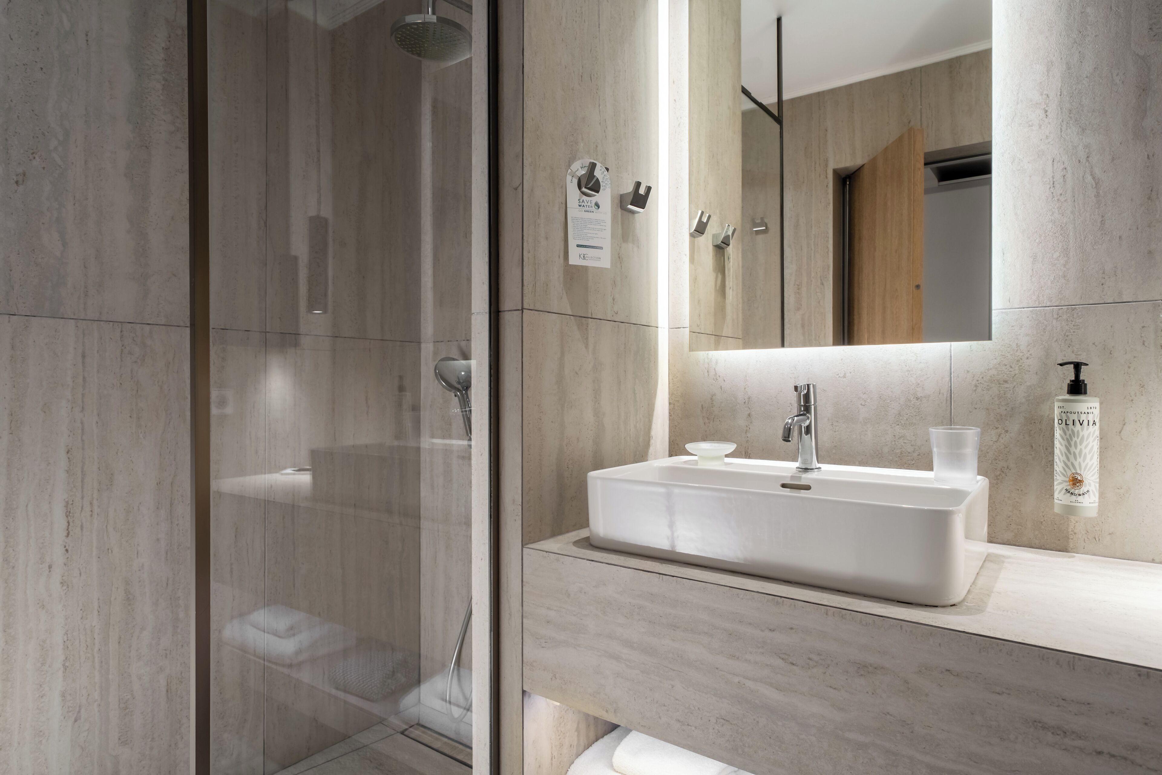 A modern bathroom with a glass-enclosed shower, a white sink, and a large mirror.