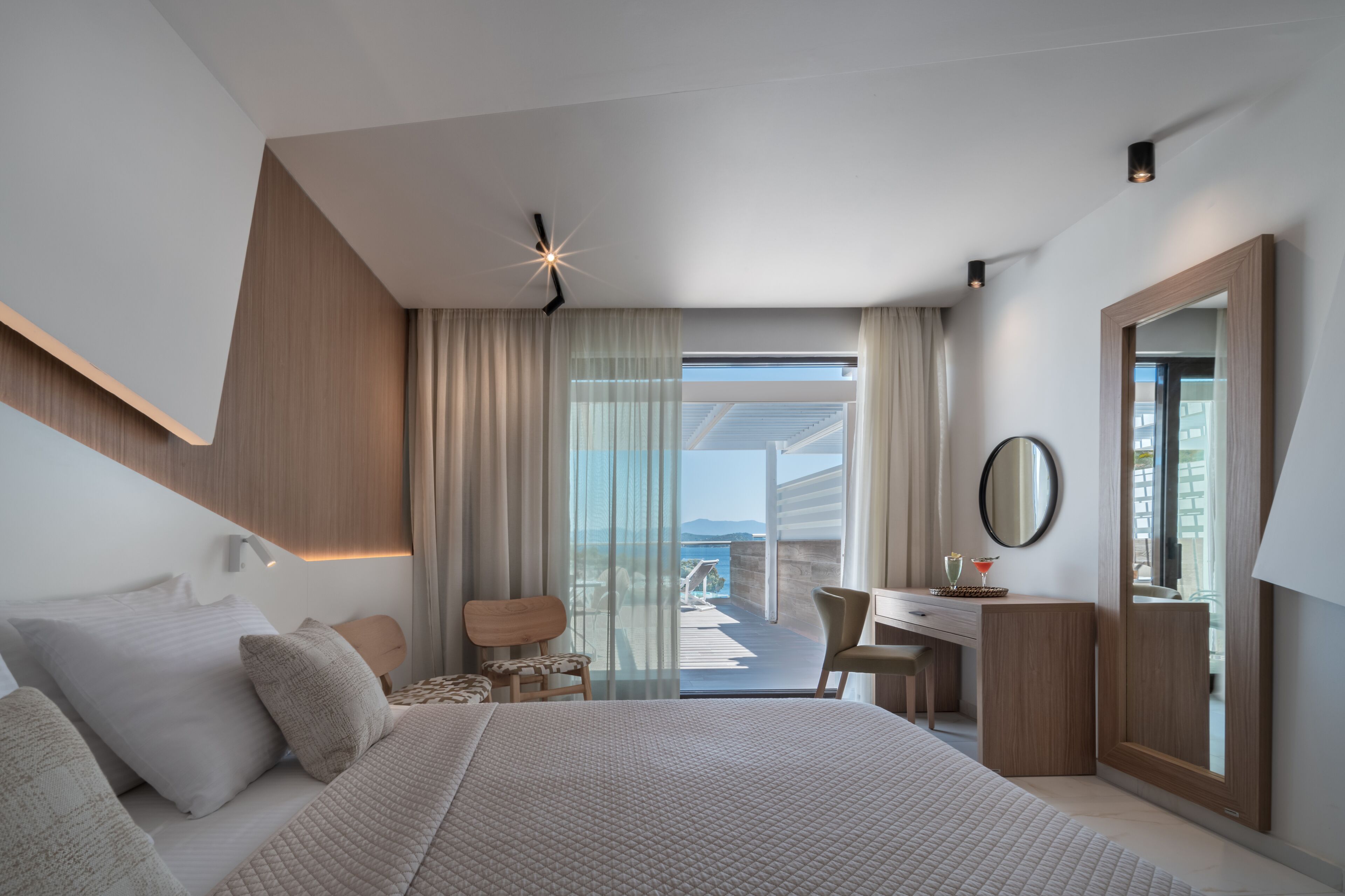 Et moderne hotelværelse med en stor seng, et skrivebord og en balkon med havudsigt.